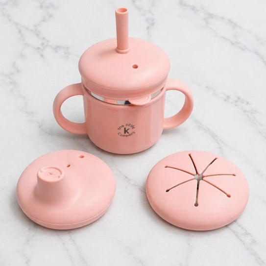Pink sippy cup with various lids on a marble surface
