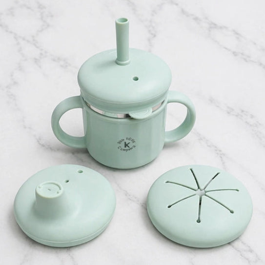 Mint green baby cup with various lids on a white marble background