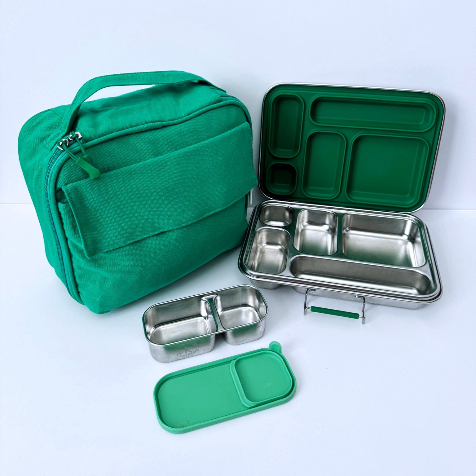 Green lunch bag and stainless steel bento box set with multiple compartments, shown on a clean white background.