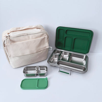 A stainless steel compartment lunch box set with a beige fabric bag, green silicone lids, and a green tray, arranged on a light gray background.